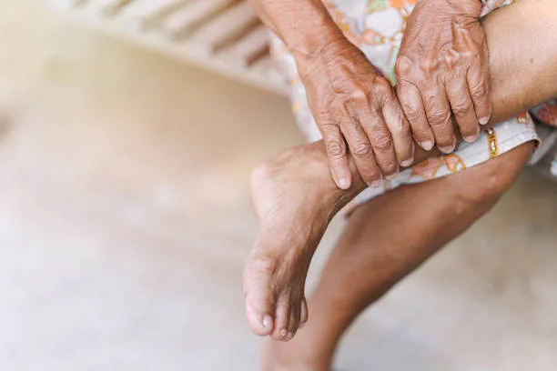 old woman uses her hands to massage her sore ankle an injury due to arthritis osteoporosis